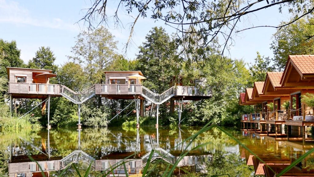 Bliock auf das Baumhaushotel Oberbayern mit Badesee